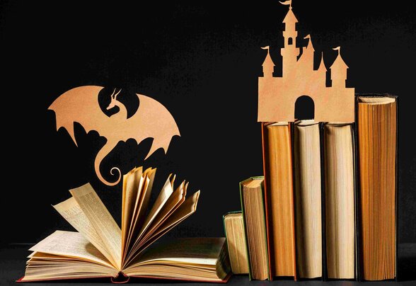 Livres ouverts avec silhouettes en papier d'un dragon et d'un château médiéval sur fond noir - Agrandir l'image, fenêtre modale