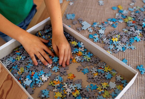 Mains d'un enfant triant des pièces de puzzle dans une boîte